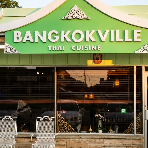 The exterior of Bangkokville Thai Cuisine restaurant with a green sign and stone facade.