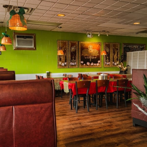 Restaurant interior with lime green walls, brown booths, red-clothed tables, and decorative hanging lamps.